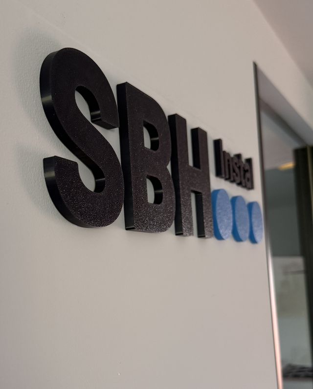 To samo logo z boku — widać grubość liter i cień na ścianie
