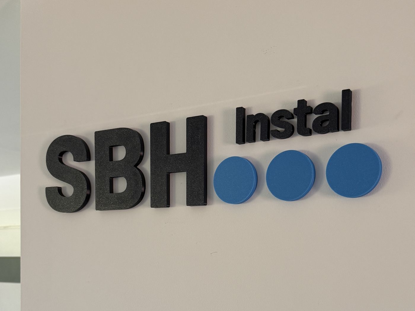 Logo SBH Instal wydrukowane w 3D i przyklejone na ścianie w biurze